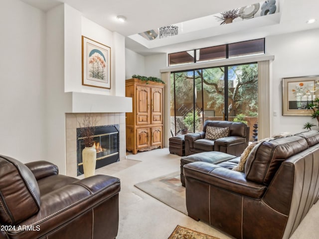 carpeted living room featuring a raised ceiling and a tile fireplace