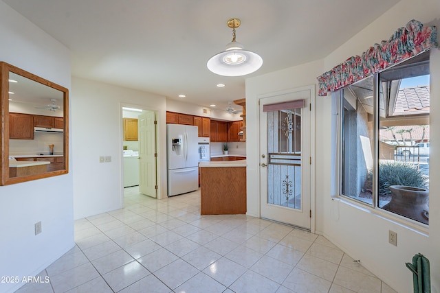 kitchen with white appliances, washer / clothes dryer, decorative light fixtures, and light tile patterned floors