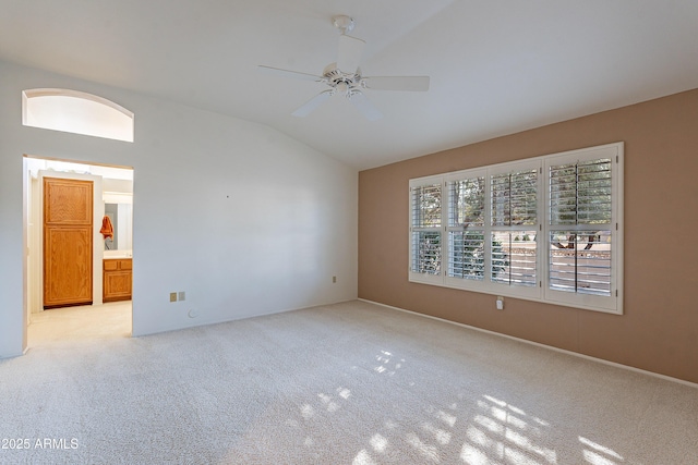 empty room featuring light colored carpet, ceiling fan, and vaulted ceiling