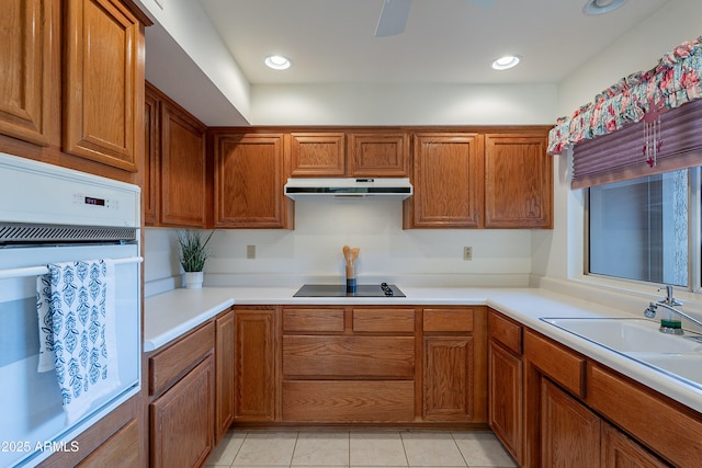 kitchen with white oven, black electric cooktop, sink, and light tile patterned floors