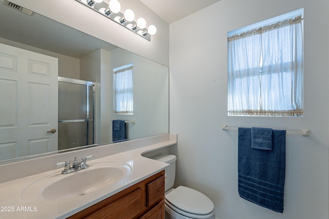 bathroom featuring toilet, a shower with shower door, and vanity