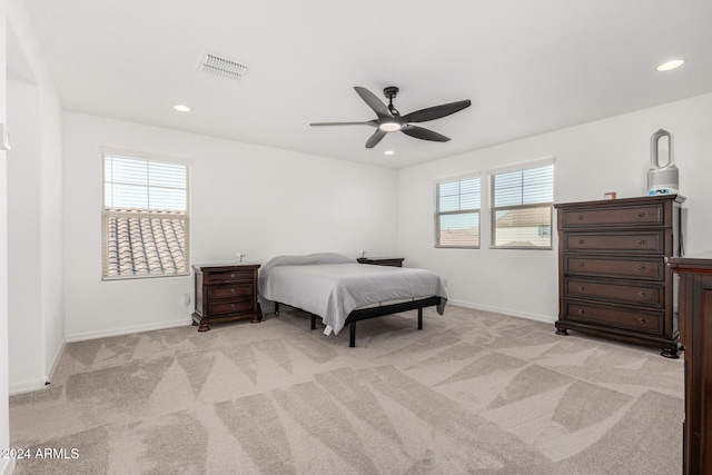 bedroom with light colored carpet, multiple windows, and ceiling fan