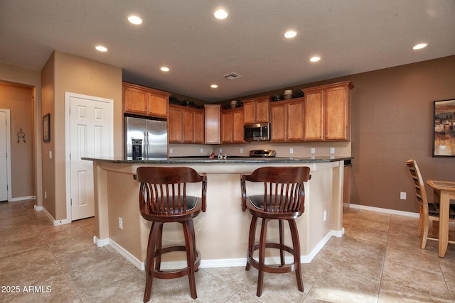 kitchen featuring appliances with stainless steel finishes, a kitchen breakfast bar, and a center island with sink