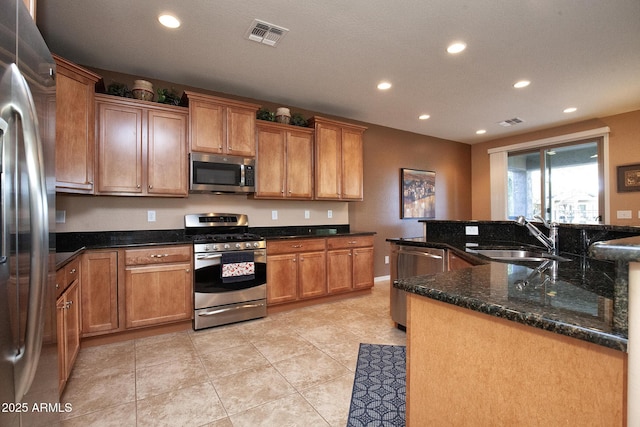 kitchen featuring light tile patterned floors, stainless steel appliances, sink, and dark stone countertops