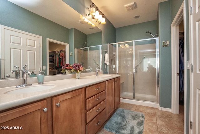 bathroom with a shower with door, vanity, and tile patterned flooring