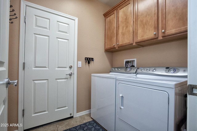 clothes washing area with light tile patterned floors, washer and clothes dryer, and cabinets