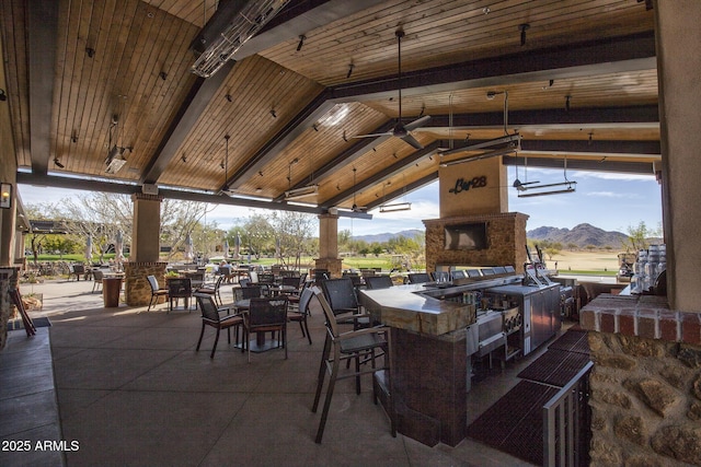 view of patio featuring exterior fireplace, a gazebo, exterior bar, a mountain view, and an outdoor kitchen