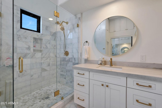 bathroom featuring a shower with shower door and vanity