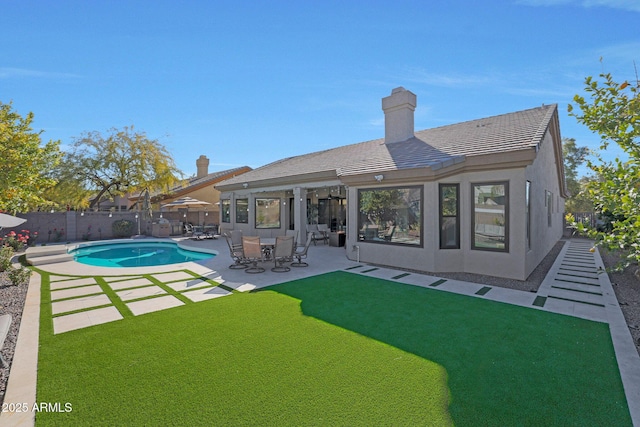 back of property featuring a fenced in pool, a patio area, and a yard