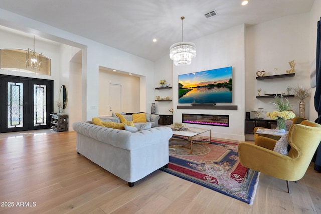 living room featuring french doors, light hardwood / wood-style flooring, and a chandelier