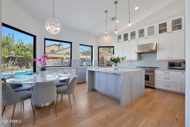 kitchen with pendant lighting, wall chimney exhaust hood, tasteful backsplash, a center island, and stainless steel appliances