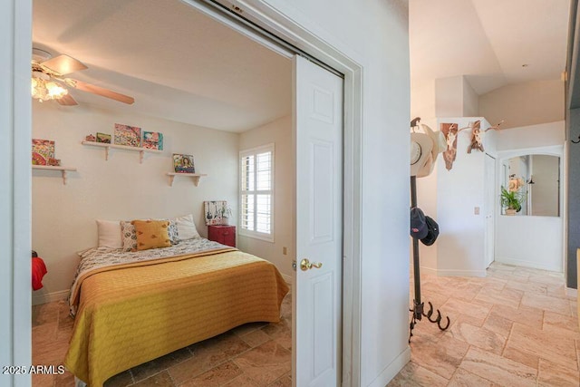 bedroom featuring ceiling fan, stone finish floor, and baseboards