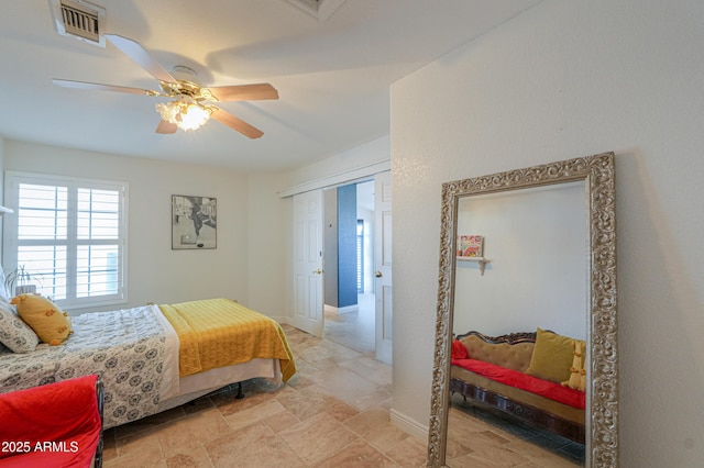 bedroom with stone finish floor, visible vents, ceiling fan, and baseboards