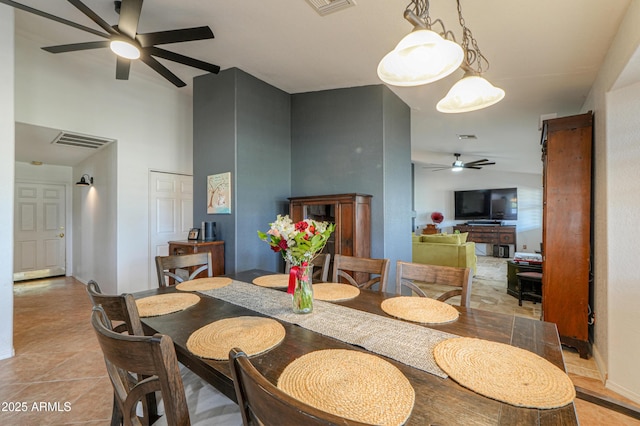 dining area with light tile patterned floors, ceiling fan, a high ceiling, and visible vents