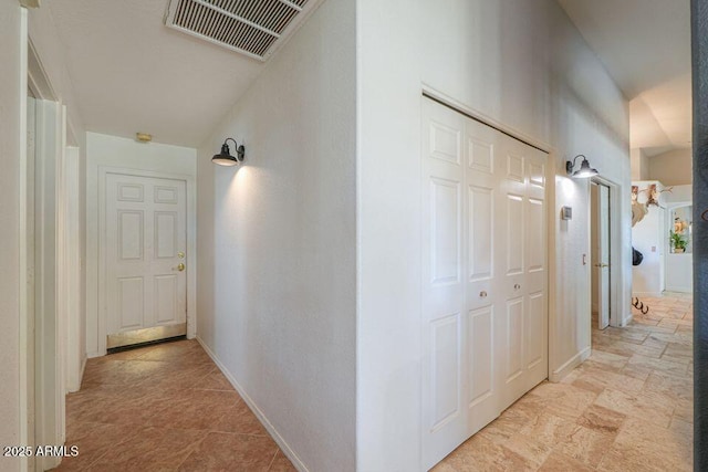 hall with stone finish flooring, visible vents, and baseboards