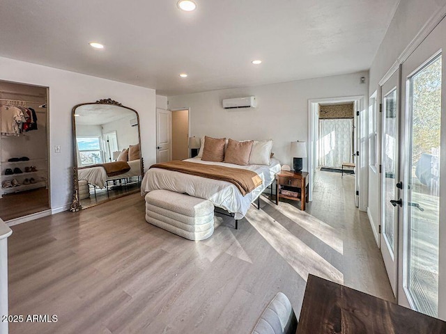 bedroom featuring recessed lighting, light wood-style flooring, and a wall mounted AC