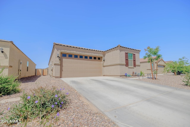 mediterranean / spanish house with a tiled roof, an attached garage, driveway, and stucco siding