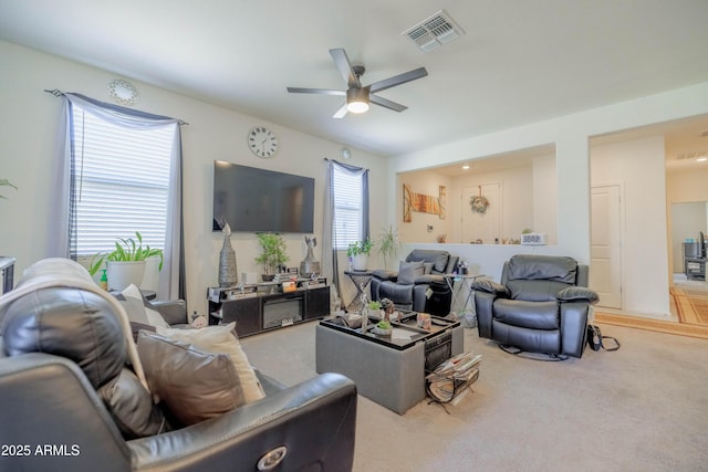 living room featuring carpet flooring, ceiling fan, and visible vents