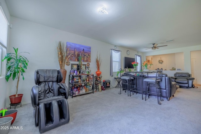 living area with a ceiling fan, visible vents, and carpet