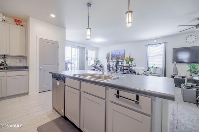 kitchen with stainless steel dishwasher, open floor plan, a sink, and a wealth of natural light