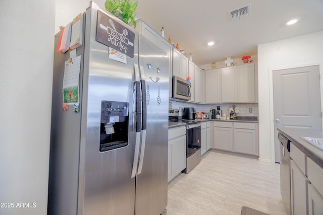 kitchen featuring appliances with stainless steel finishes, light wood-style flooring, recessed lighting, backsplash, and visible vents