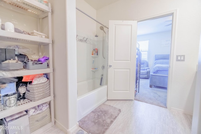 bathroom with shower / bath combination, baseboards, and wood finished floors
