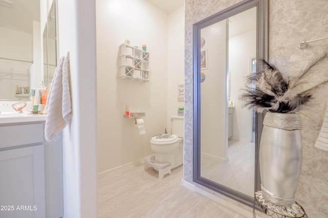 bathroom featuring toilet, baseboards, and vanity