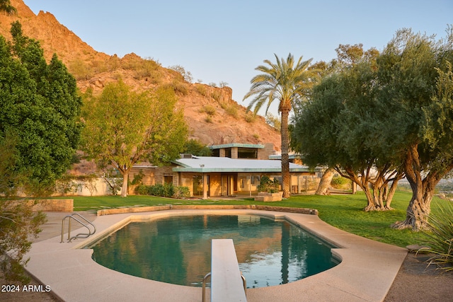 view of swimming pool featuring a mountain view, a patio, a diving board, and a yard