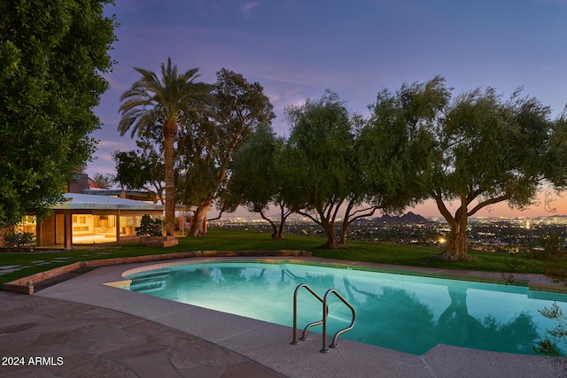 pool at dusk with a lawn and a patio