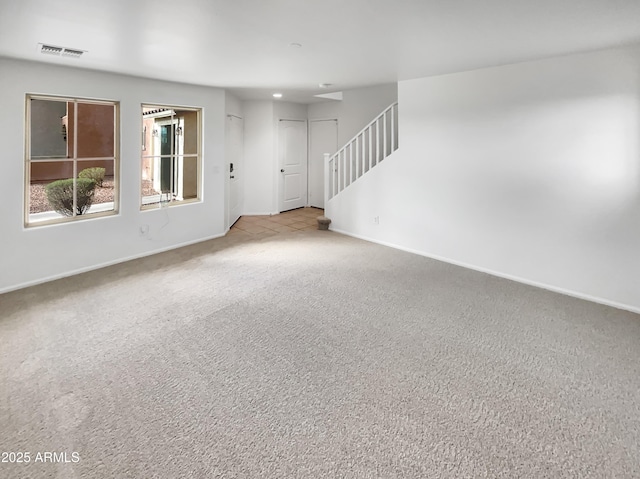 unfurnished living room featuring stairway, baseboards, visible vents, and carpet floors