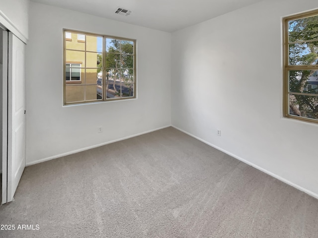 unfurnished bedroom featuring visible vents, multiple windows, baseboards, and carpet flooring