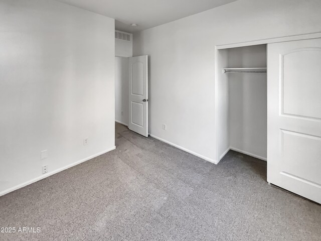 unfurnished bedroom featuring baseboards, visible vents, a closet, and carpet floors