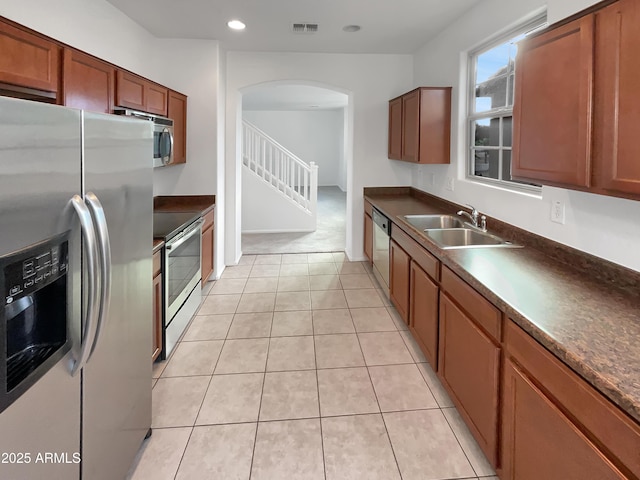 kitchen with dark countertops, visible vents, appliances with stainless steel finishes, arched walkways, and a sink