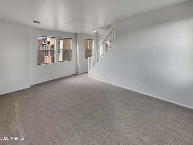 unfurnished room with carpet, stairway, baseboards, and visible vents