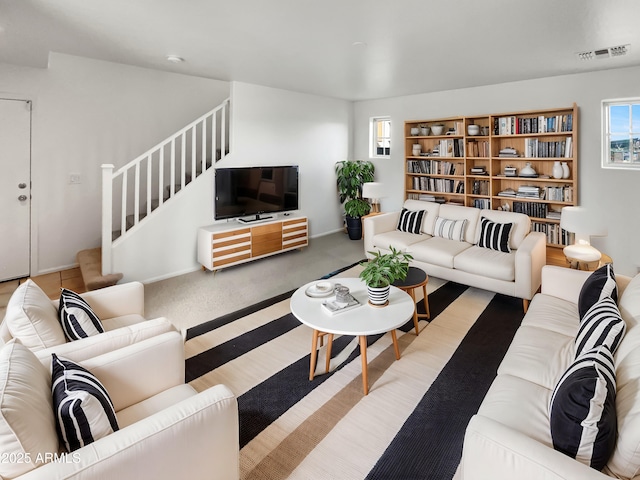 living area with visible vents, stairs, and carpet