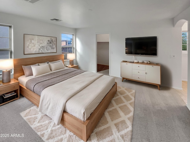 bedroom with a spacious closet, multiple windows, visible vents, and light carpet