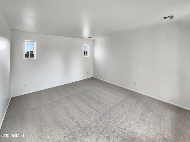 unfurnished room featuring a healthy amount of sunlight, visible vents, carpet floors, and baseboards