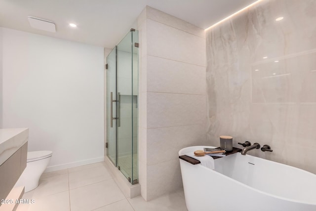 bathroom with a stall shower, tile patterned flooring, a soaking tub, toilet, and vanity