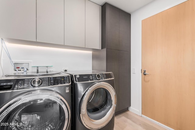 laundry area with washer and clothes dryer, cabinet space, light wood finished floors, and baseboards