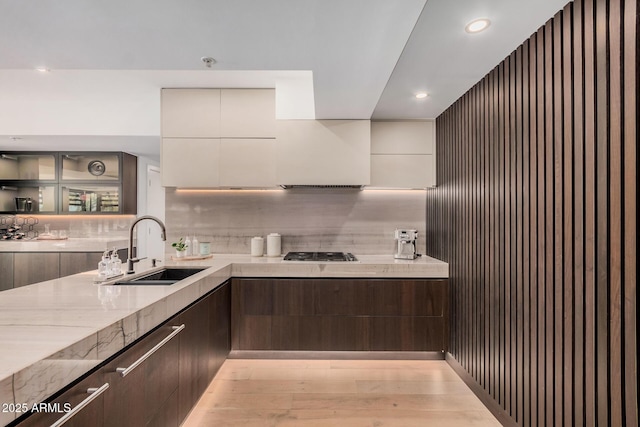 kitchen with a sink, modern cabinets, dark brown cabinetry, stainless steel gas cooktop, and recessed lighting