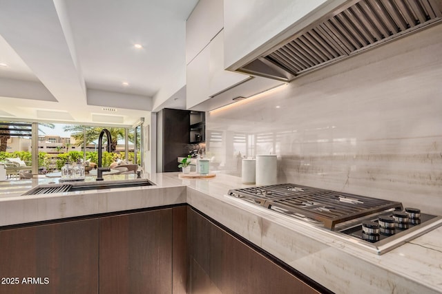 kitchen with premium range hood, a sink, decorative backsplash, light countertops, and stainless steel gas stovetop