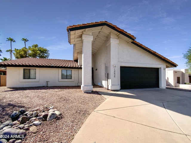 mediterranean / spanish-style home featuring driveway, an attached garage, a tiled roof, and stucco siding