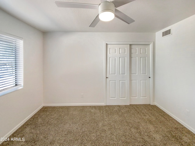 unfurnished bedroom featuring carpet floors, ceiling fan, and a closet