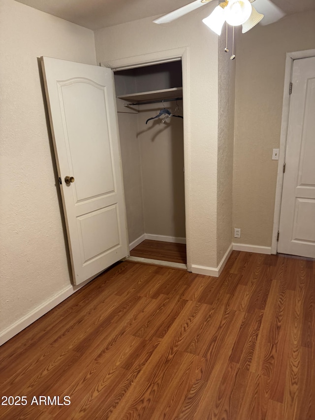 unfurnished bedroom featuring hardwood / wood-style flooring, ceiling fan, and a closet