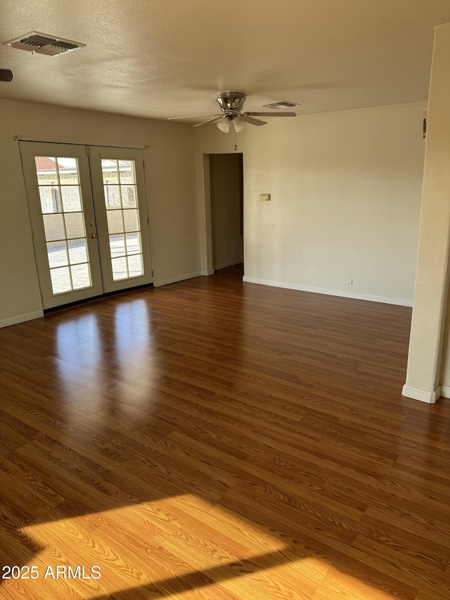 unfurnished room featuring ceiling fan, dark wood-type flooring, french doors, and a textured ceiling