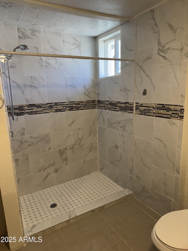 bathroom with tiled shower, tile patterned floors, and toilet