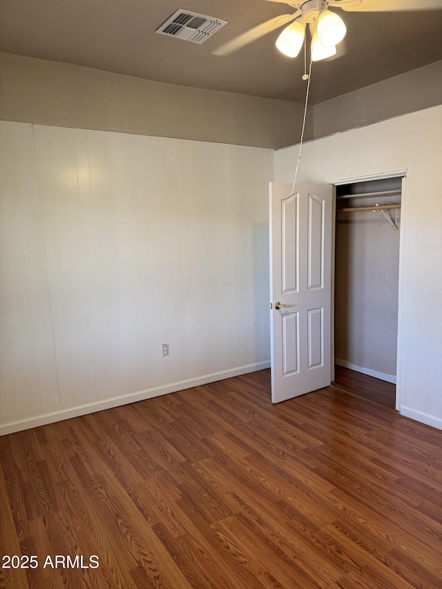 unfurnished bedroom featuring ceiling fan, dark hardwood / wood-style flooring, and a closet