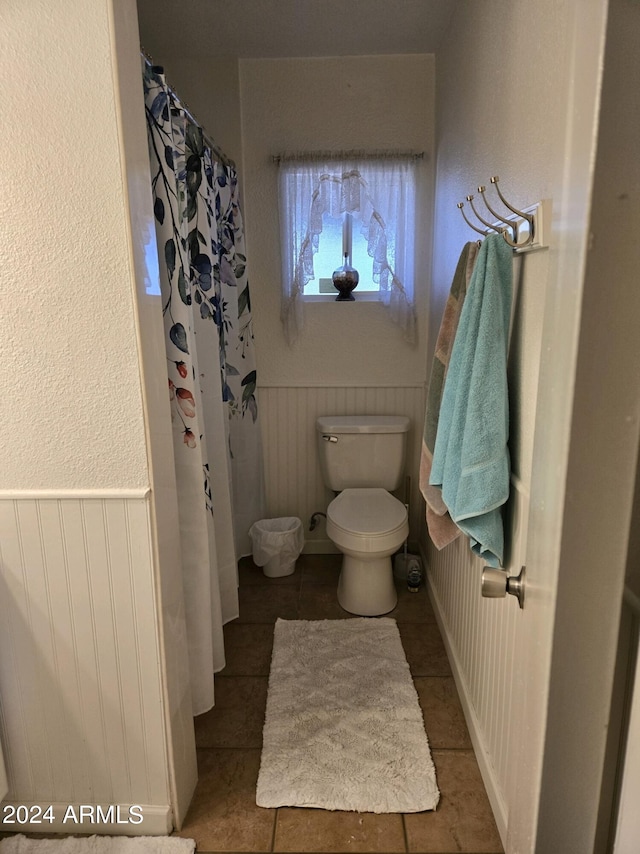 full bathroom with toilet, a shower with shower curtain, and wainscoting