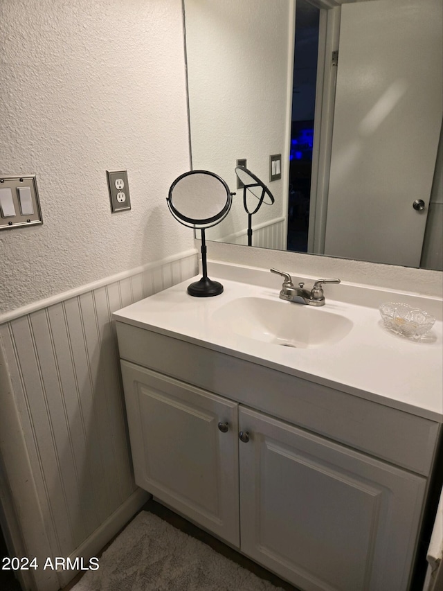 bathroom featuring a textured wall, wainscoting, and vanity