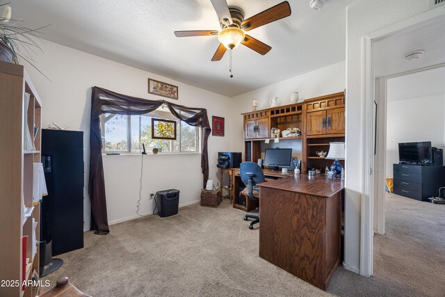 carpeted office space with a ceiling fan